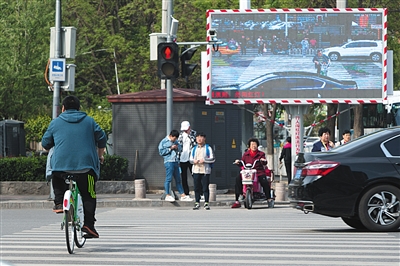 4月24日，闯红灯违法行为警示设施正在抓拍闯红灯的行人，被抓拍的违章者照片显示在屏幕上。